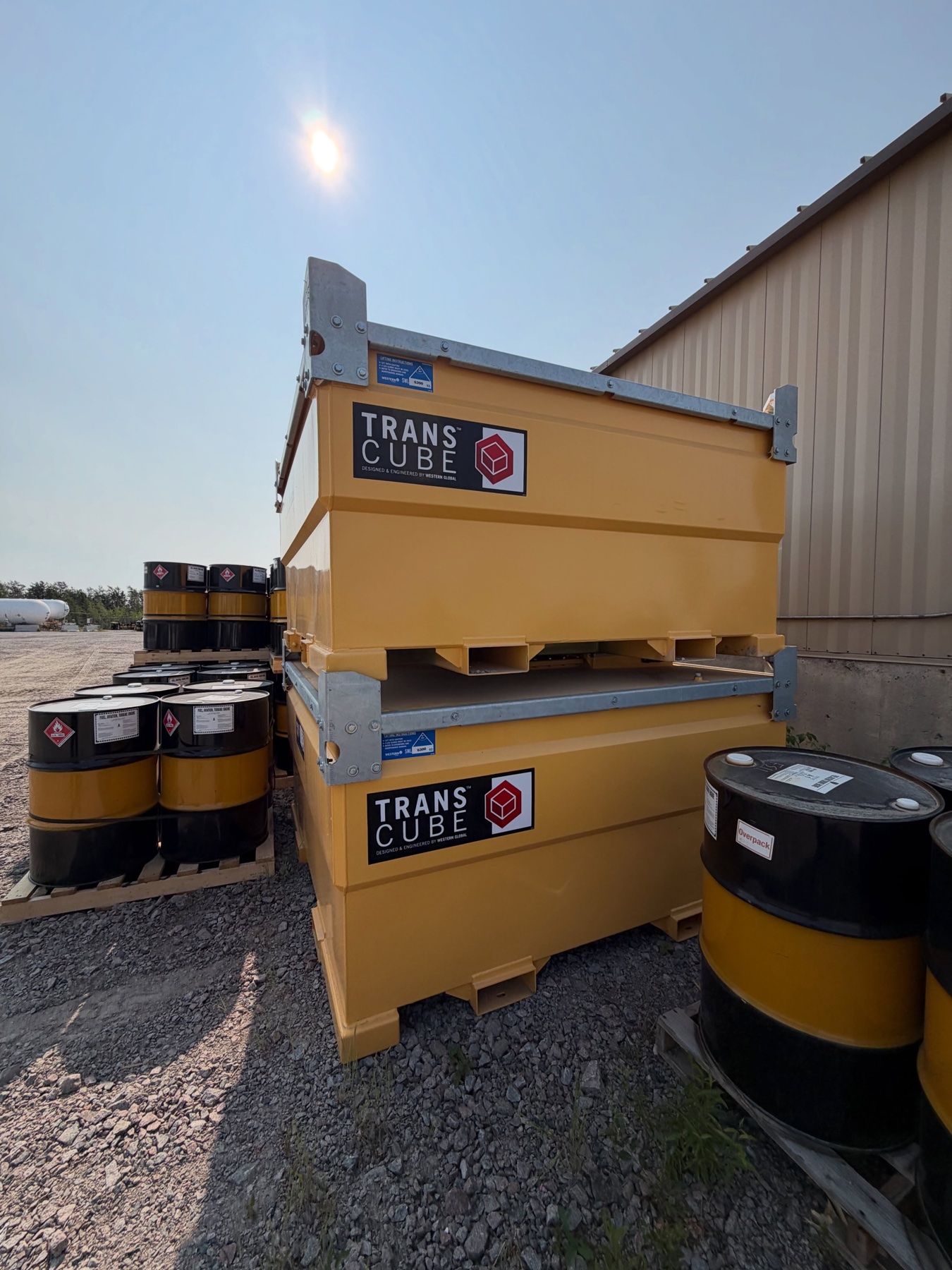Yellow Western Global TransCube tanks stacked beside fuel drums